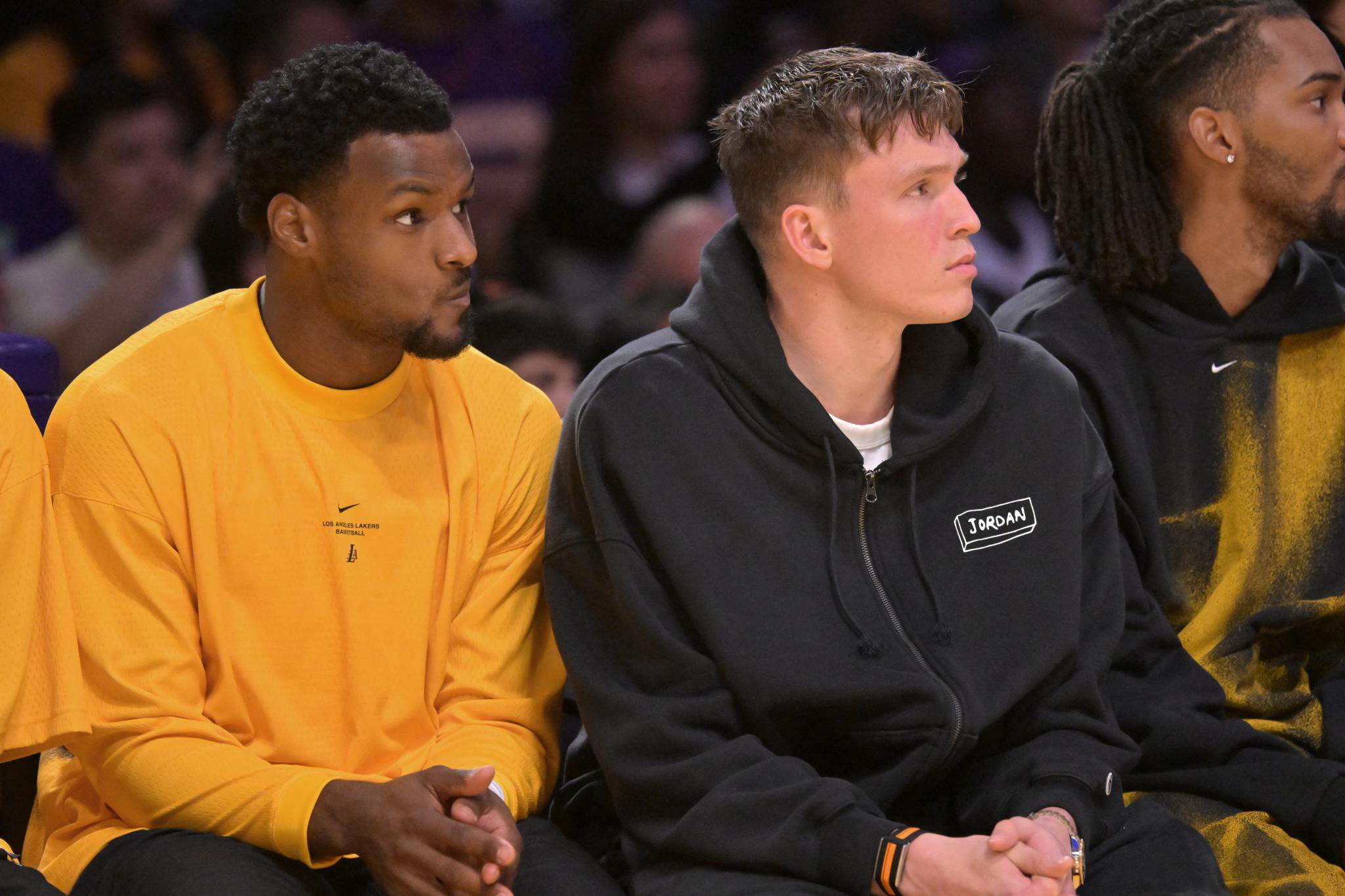 Los Angeles Lakers guard Bronny James and forward Dalton Knecht look on from the bench during a game.
