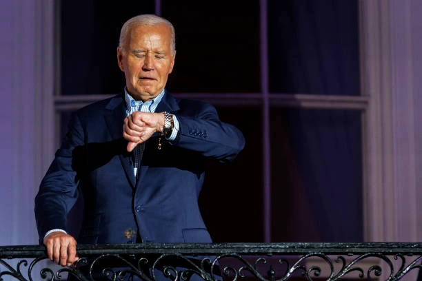 President Joe Biden checks his watch as he steps out onto the balcony of the White House to view the fireworks over the National Mall during a 4th of...