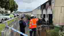 Emergency services members assess the badly damaged property, with police tape cordoning off the area around the house