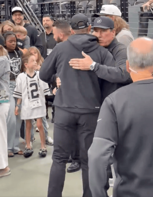 Tom Brady hugging Antonio Pierce in a stadium.