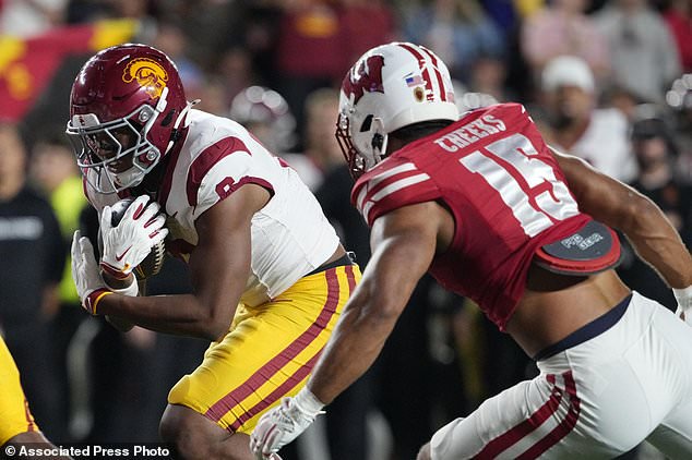 Southern California running back Deshonne Redeaux, left, runs the ball while defended by Wisconsin linebacker Sebastian Cheeks (15) during an NCAA college football game, Saturday, Oct. 24, 2026, in Madison, Wis. (AP Photo/Ross Harried)