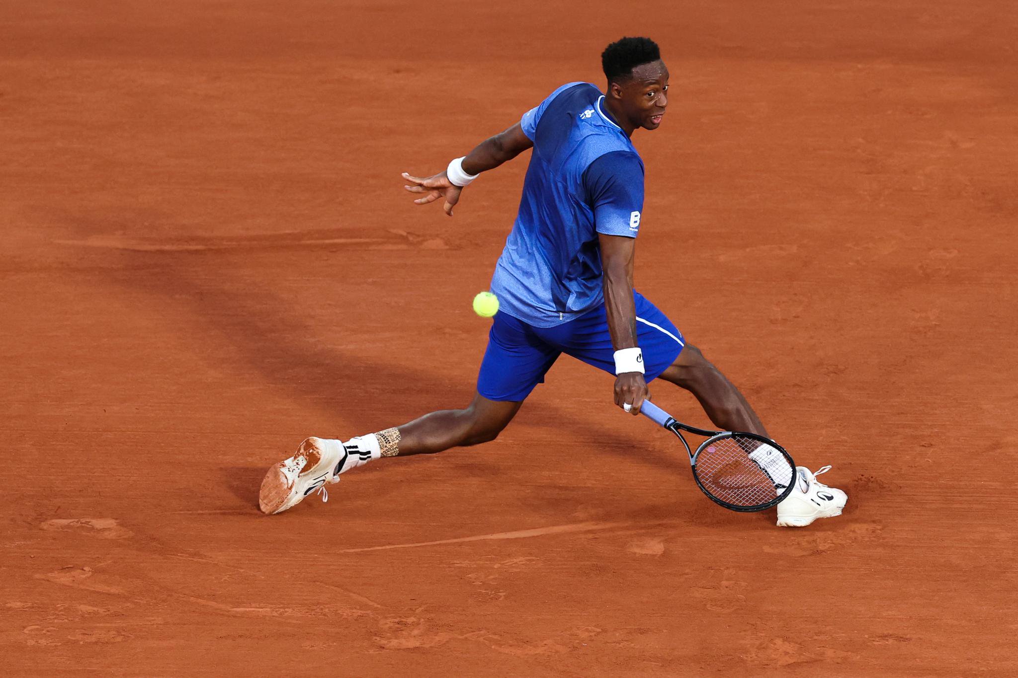 Gael Monfils plays a backhand return during a French Open match on clay.