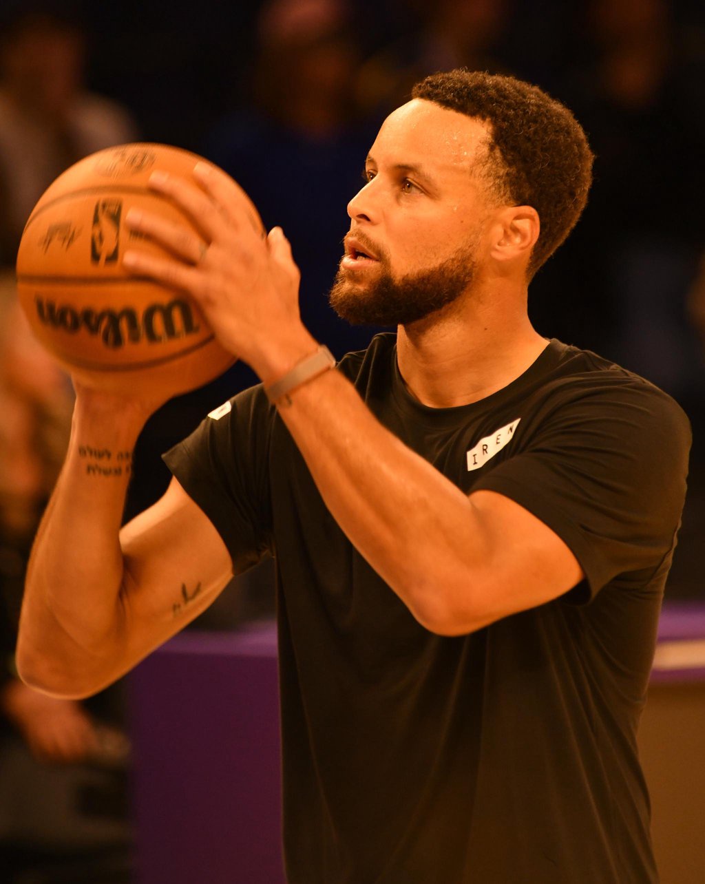 Steph Curry warming up with a basketball on the court.