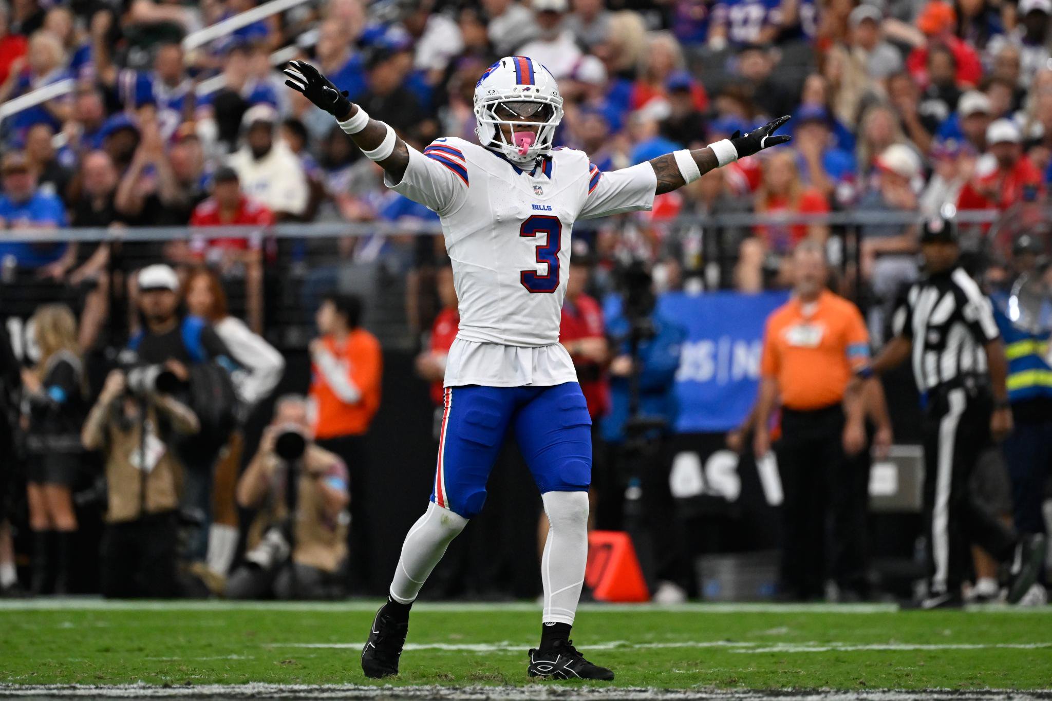 Damar Hamlin in uniform on the field with arms raised.