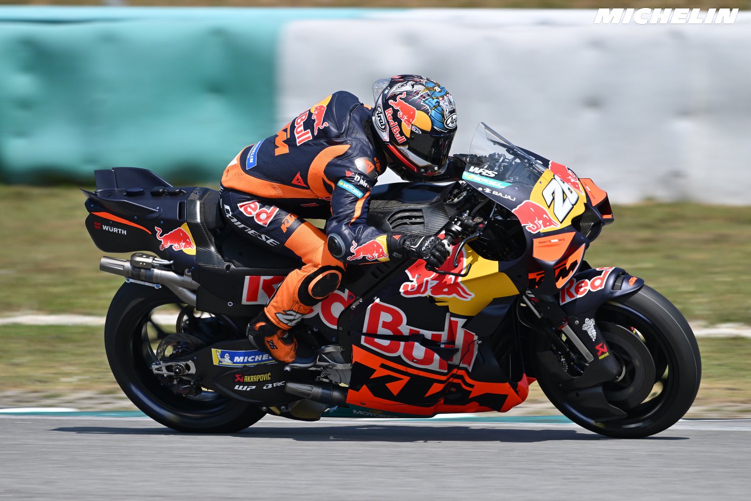 Rider in KTM Red Bull leathers and helmet on a KTM MotoGP bike, leaning into a corner on track, race number 27 visible