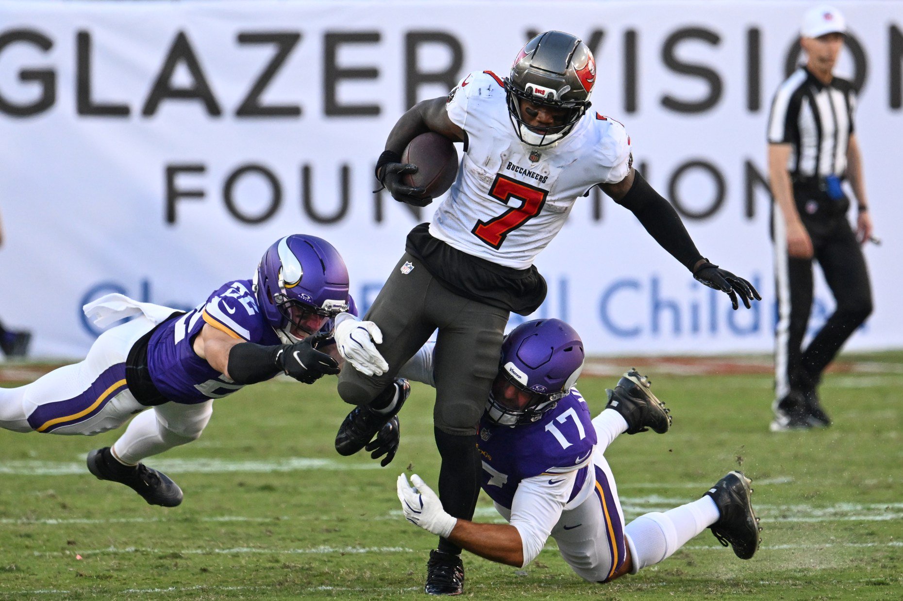 Tampa Bay Buccaneers running back Bucky Irving (7) is tackled by Minnesota Vikings safety Harrison Smith (22) and linebacker Kyle van Noy (17) during the second half of an NFL football game in Tampa, Fla., Sunday, Sept. 27, 2026. (AP Photo/Jason Behnken)