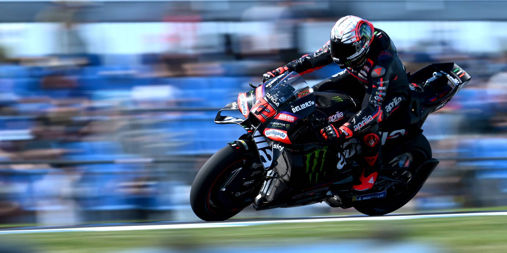 MotoGP-Fahrer Marco Bezzecchi lehnt sich in hoher Geschwindigkeit auf seiner schwarzen Aprilia in eine Kurve auf dem Circuit von Phillip Island.