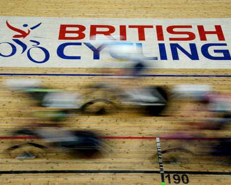 Blurred cyclists race past on a velodrome track during a British Cycling event