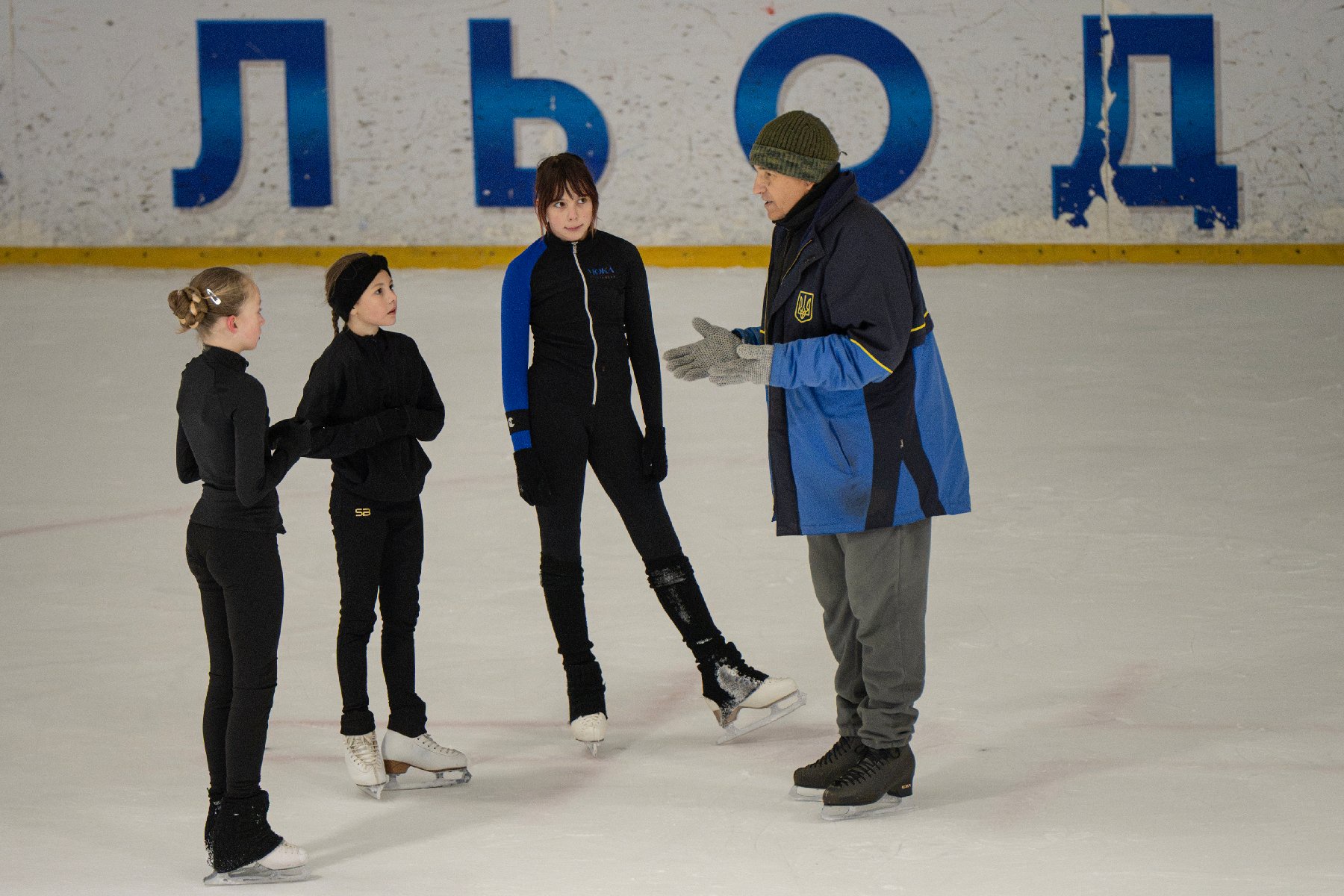 L'entraîneur ukrainien Oleksandre Toumanovsky parle avec trois jeunes patineuses, à Kiev, le 16 octobre 2026