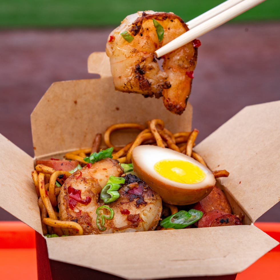 Takeout container filled with shrimp, noodles, and a halved egg.