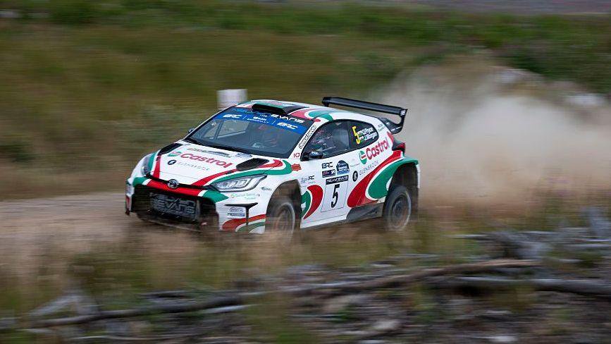 A white green and red Toyota Yaris rally car on a gravel track.
