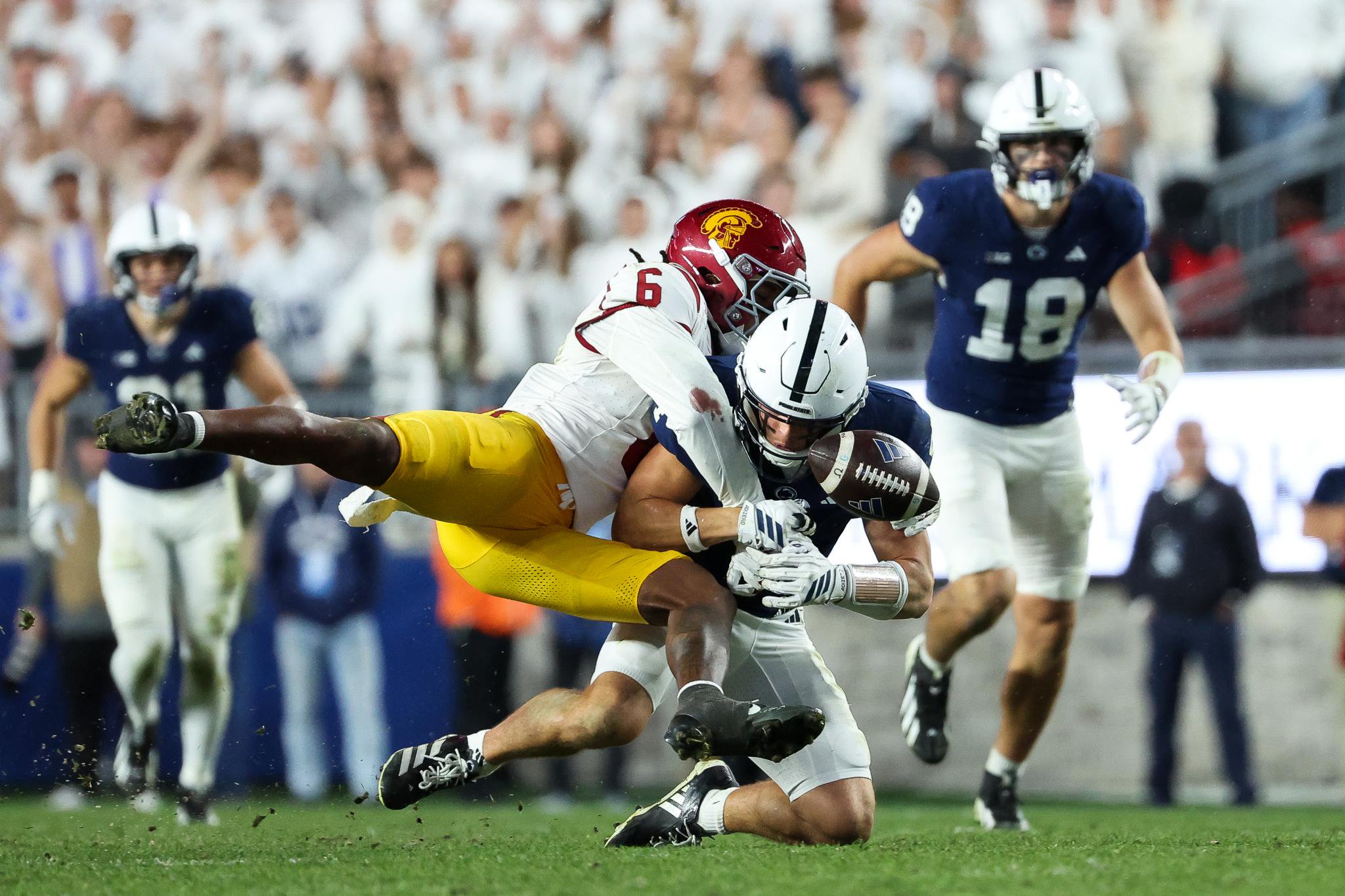 A football player in a USC uniform tackles a Penn State player to the ground.