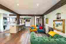 The open plan kitchen and living area, with two mismatching coloured armchairs and a love seat 
