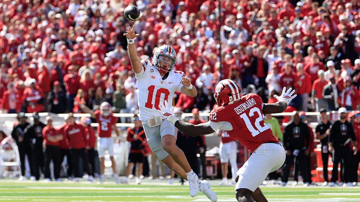 Julian Sayin #10 looks to throw over Tobi Osunsanmi #12 during a football game.