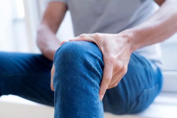 A photo of a man holding his leg