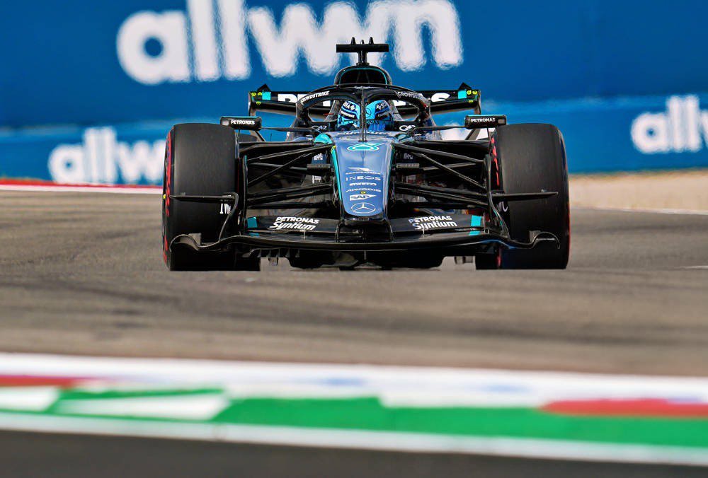 George Russell in his black and teal Mercedes F1 car on track at the US Grand Prix, with Mercedes and Petronas livery visible.