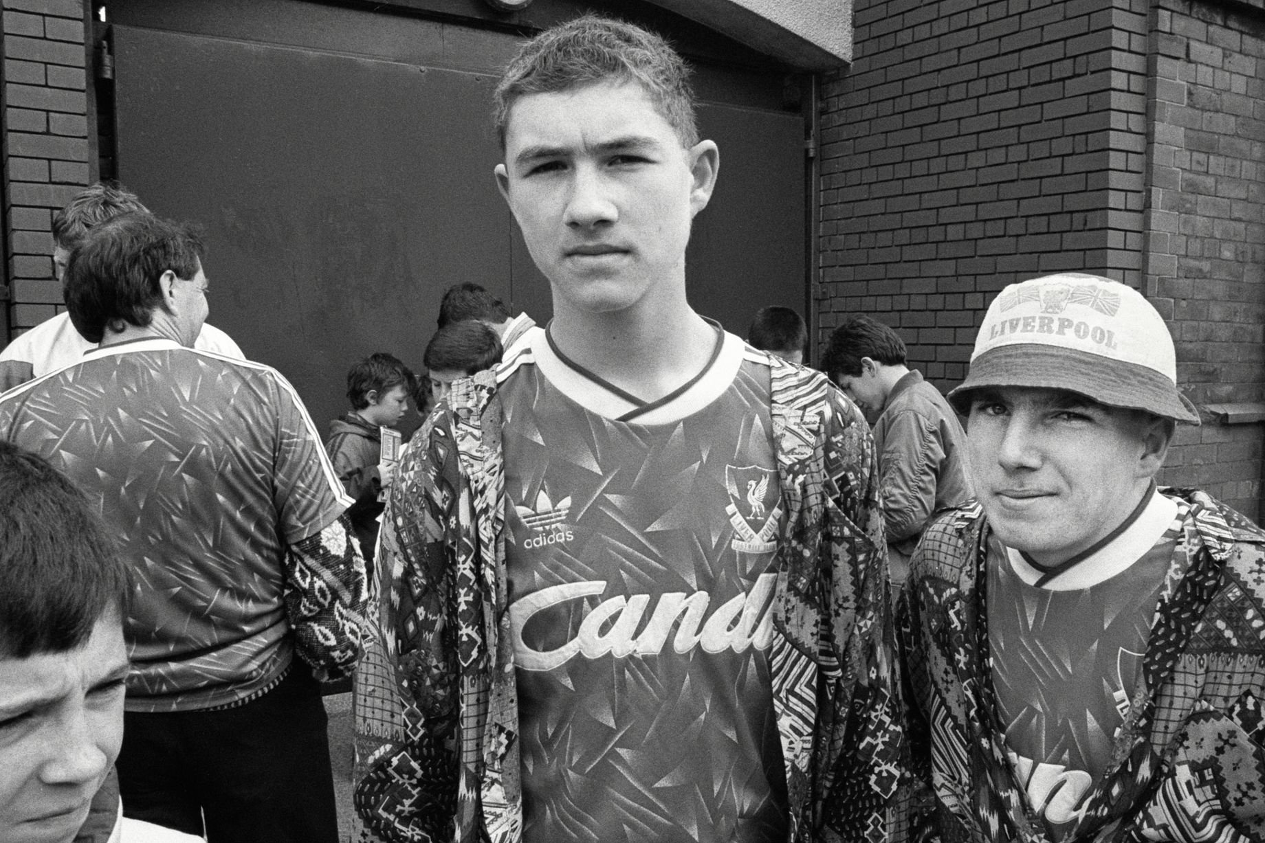 In 1991, photographer Richard Davis followed supporters from across the North West for a book about football, fashion and music. Richard spent much of the season taking pictures of fans from Liverpool, Everton and more for the book Football With Attitude. In collaboration with Lower Block, the Going to the Match zine has been published to coincide with an exhibition of the same name at Bury Art Museum, running from October 2024 to March 2025.
Pictured: Liverpool Fans at Anfield, 1991