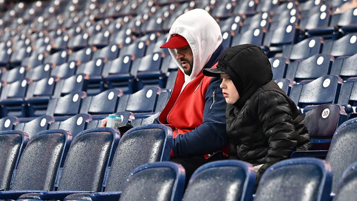 Fans sit in the stands after game postponement at Progressive Field.