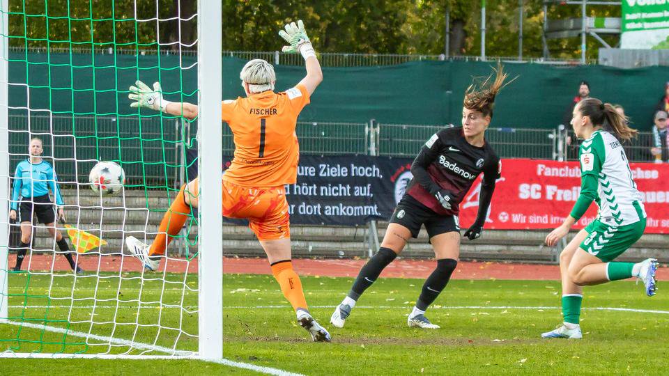 Ein Fußball-Torhüterin versucht, den Ball vor dem Einschlag ins Netz mit dem Fuß zu parieren.
