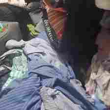 Its face can be seen between the piles of clothes in the closet