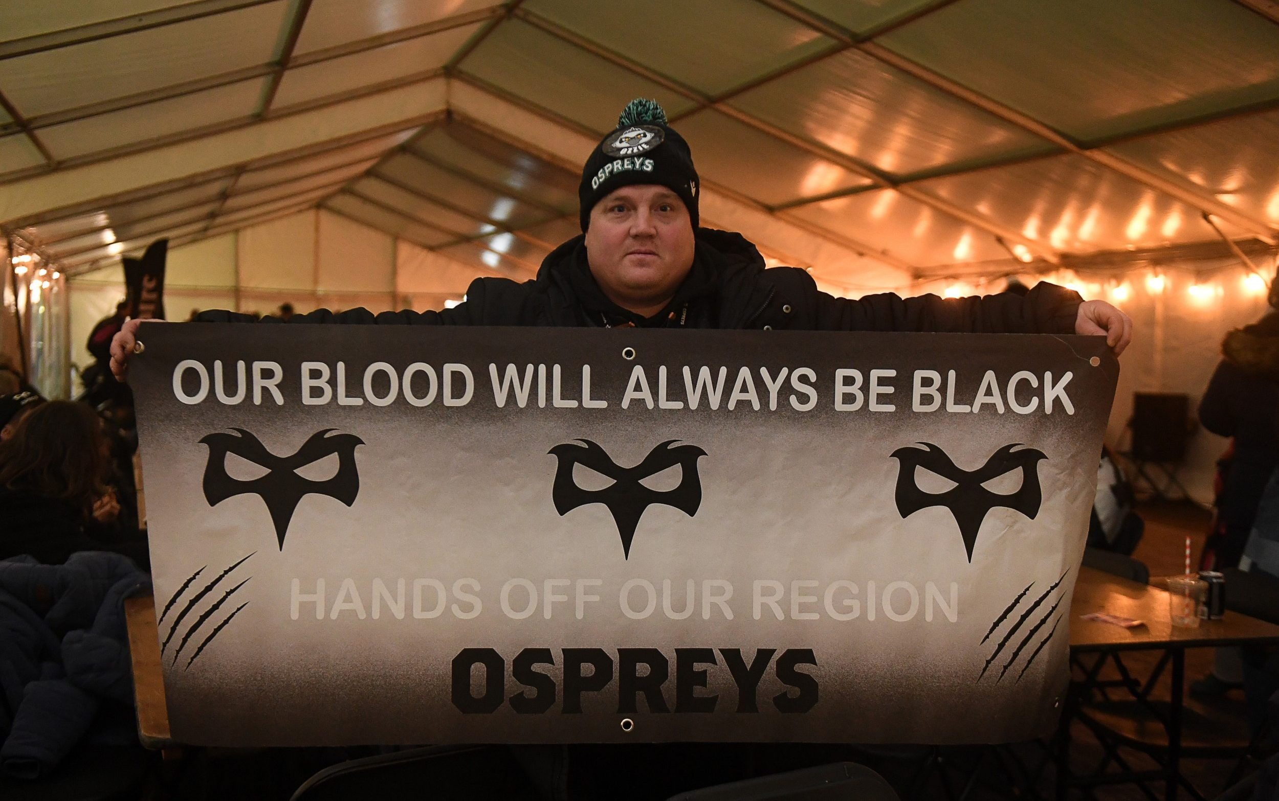 An Ospreys fan holding up a flag in protest of the worries