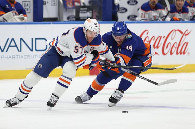 Edmonton Oilers' Connor McDavid (97) and New York Islanders' Bo Horvat (14) battle for the puck during the first period of an NHL hockey game Saturday, Oct. 31, 2026, in Elmont, N.Y. (AP Photo/Pamela Smith)