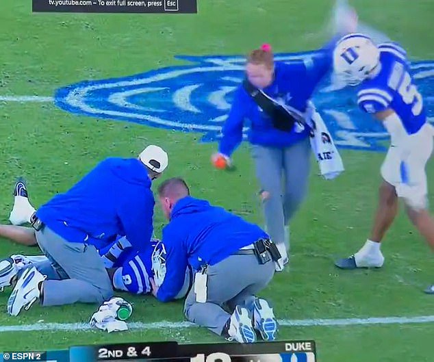 College football fans were left stunned on Saturday after a Duke star was seen swiping at a young female staffer while she attempted to provide medical attention to a player