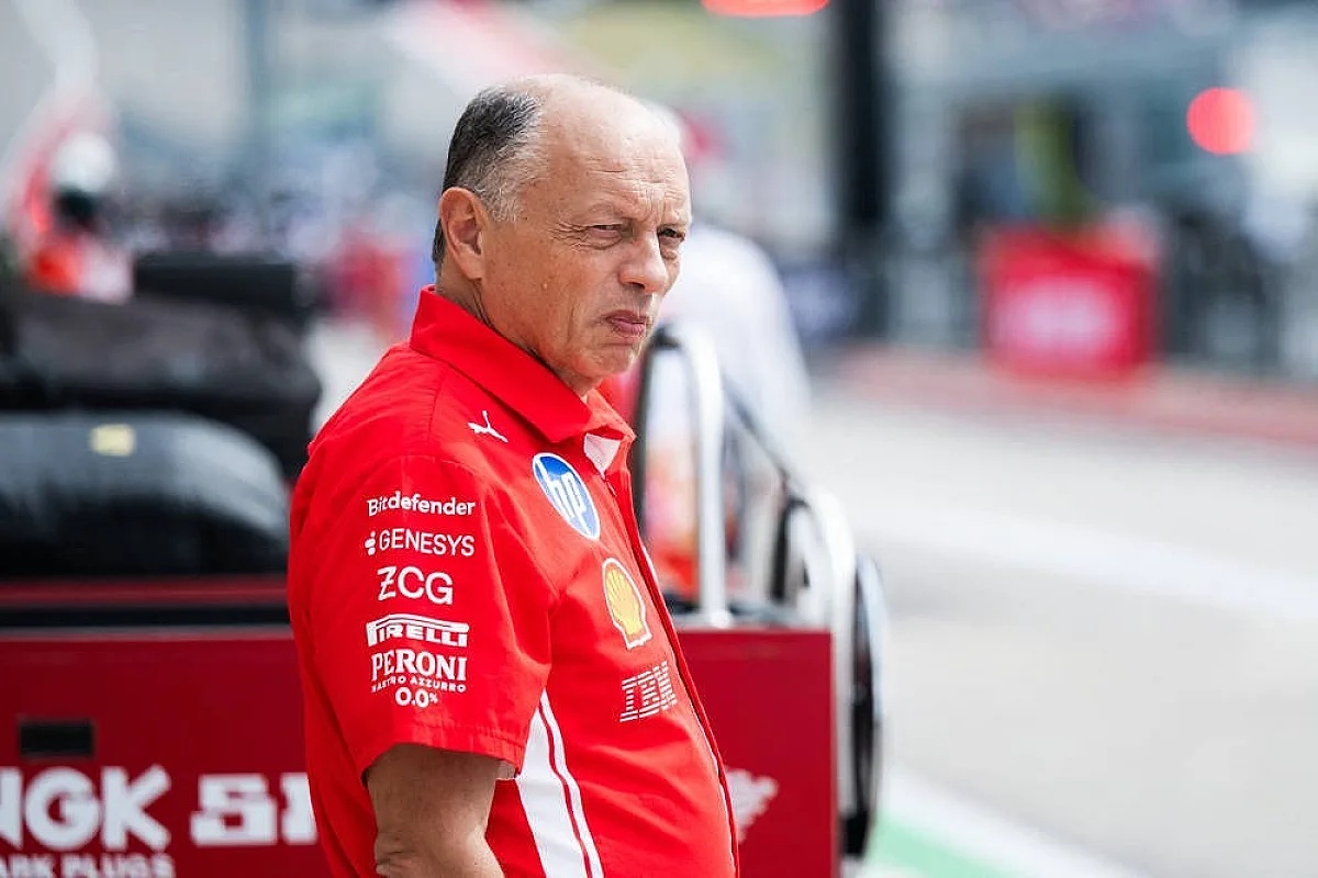 Man in red Ferrari team shirt with Shell, Pirelli, and Genesys logos standing in the pit lane, Formula 1 paddock