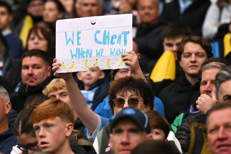 A Man City fan holds up a sign reading We cheat when we want during the English Premier League football match between Manchester City and Ipswich Town at the Etihad Stadium in Manchester, north west England, on October 17, 2026. (Photo by Oli SCARFF / AFP) / RESTRICTED TO EDITORIAL USE. NO USE WITH UNAUTHORIZED AUDIO, VIDEO, DATA, FIXTURE LISTS, CLUB/LEAGUE LOGOS OR 'LIVE' SERVICES. ONLINE IN-MATCH USE LIMITED TO 120 IMAGES. AN ADDITIONAL 40 IMAGES MAY BE USED IN EXTRA TIME. NO VIDEO EMULATION. SOCIAL MEDIA IN-MATCH USE LIMITED TO 120 IMAGES. AN ADDITIONAL 40 IMAGES MAY BE USED IN EXTRA TIME. NO USE IN BETTING PUBLICATIONS, GAMES OR SINGLE CLUB/LEAGUE/PLAYER PUBLICATIONS. /