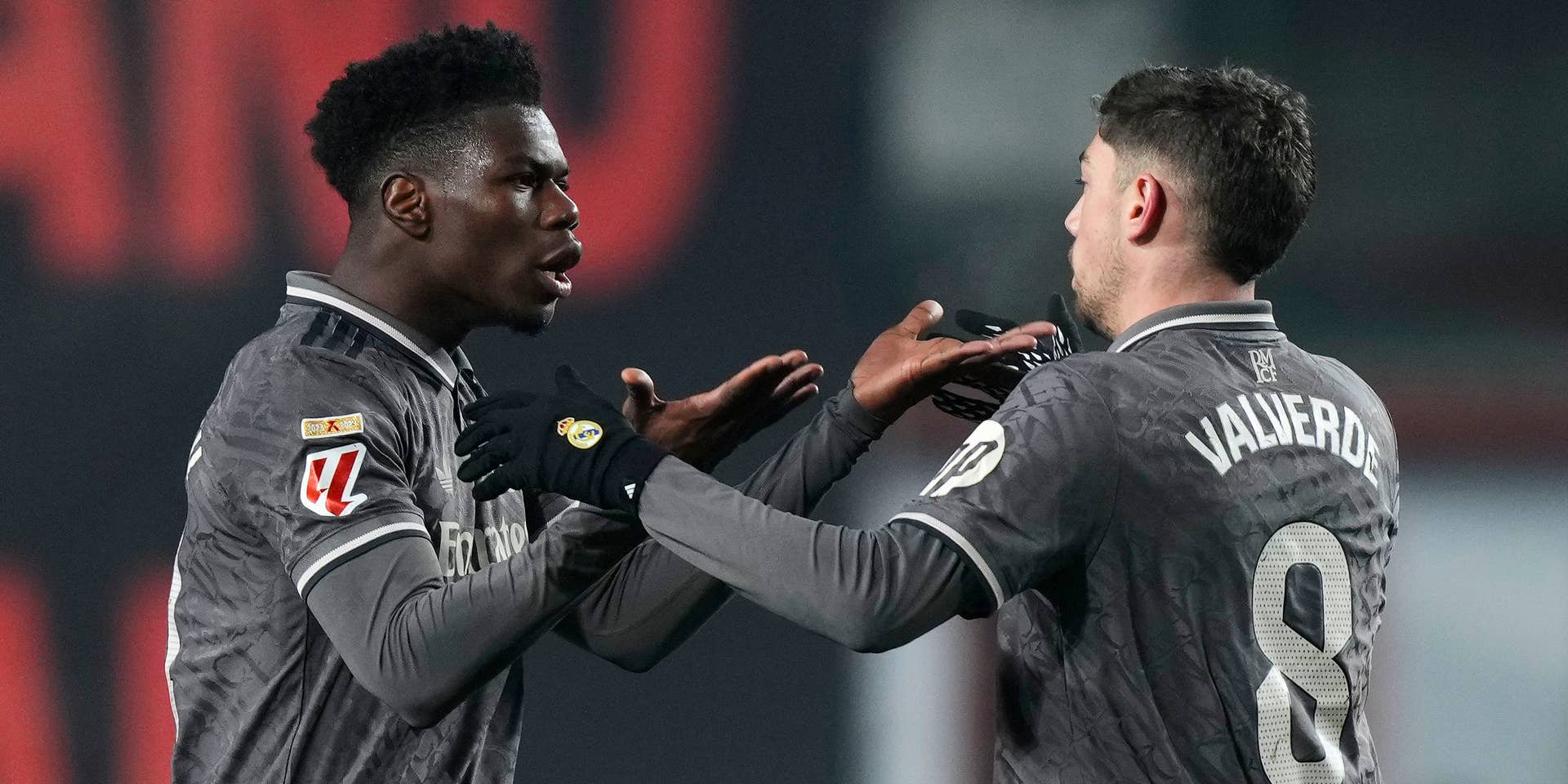 Aurélien Tchouaméni und Federico Valverde im grauen Auswärtstrikot von Real Madrid Gestikulieren intensiv im Gespräch auf dem Spielfeld.