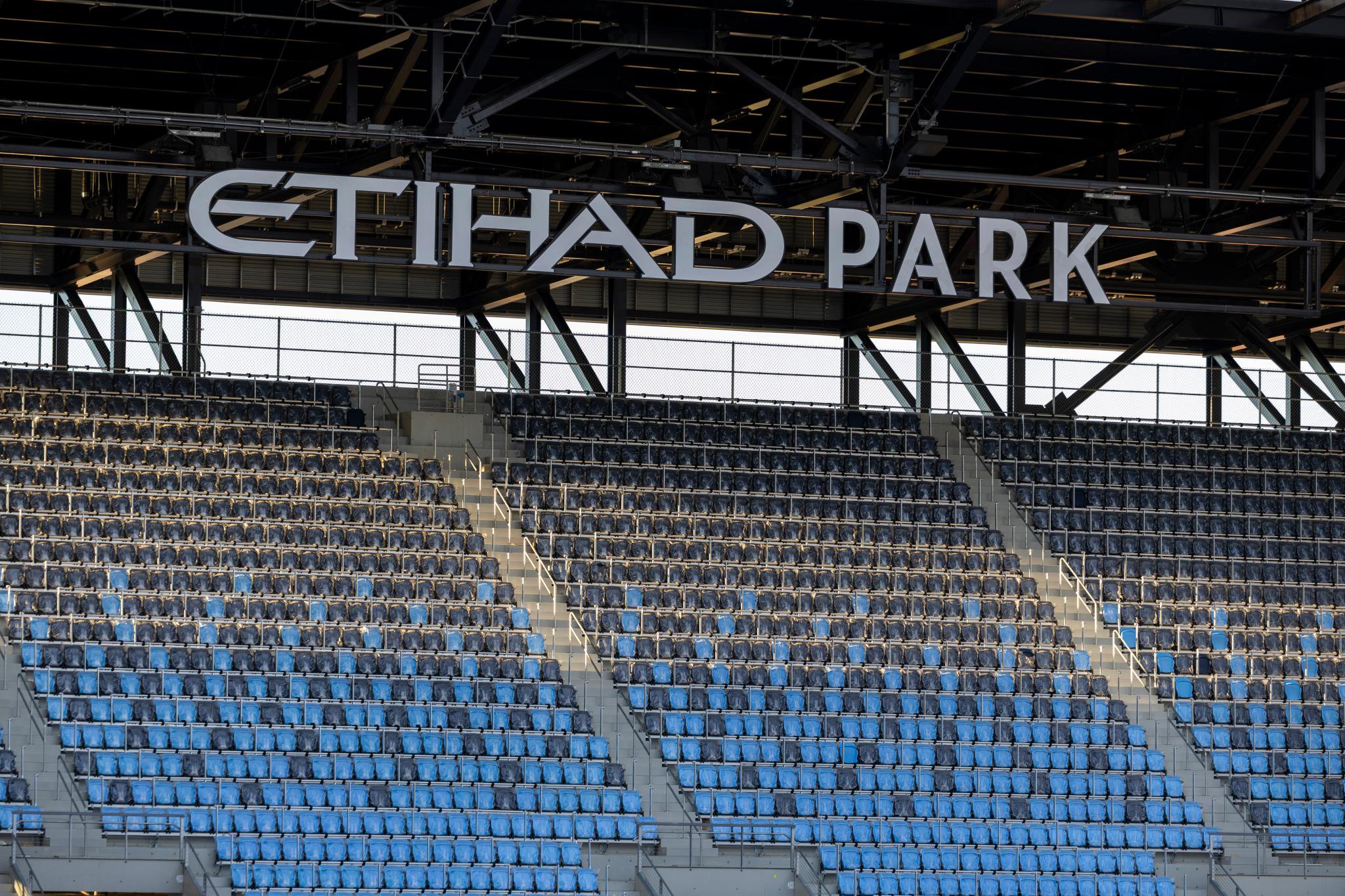 Rows of stadium seating and the "Etihad Park" sign under the roof structure.