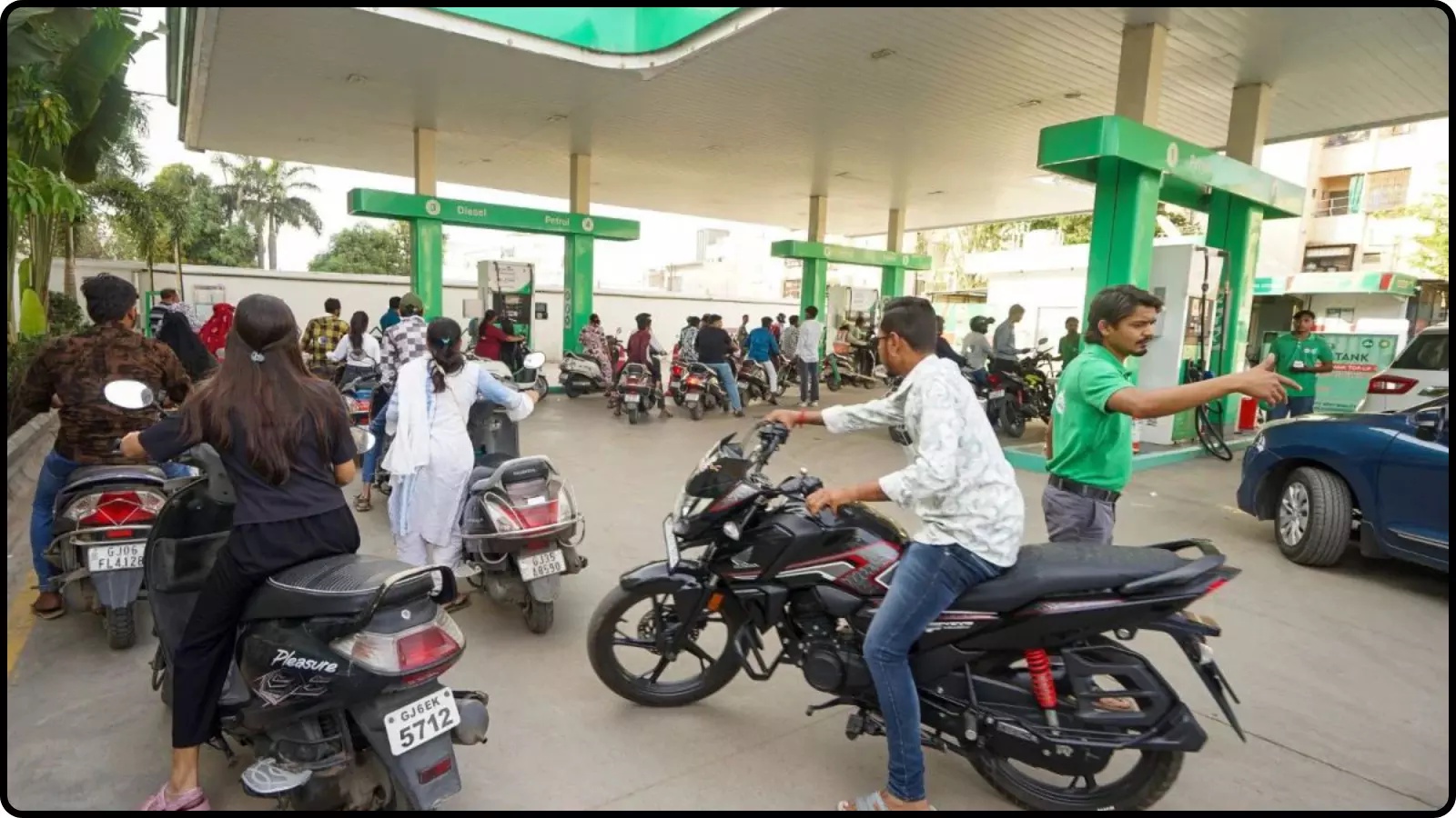 पेट्रोल पंप पर मोटरसाइकिल और स्कूटर में ईंधन भरवाते लोग भारत में तेल की कीमतों के संदर्भ में।