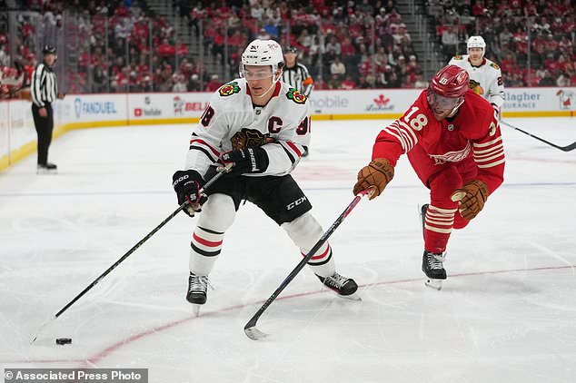 Chicago Blackhawks center Connor Bedard (98) protects the puck from Detroit Red Wings center Andrew Copp (18) in the second period of an NHL hockey game Thursday, Oct. 29, 2026, in Detroit. (AP Photo/Paul Sancya)