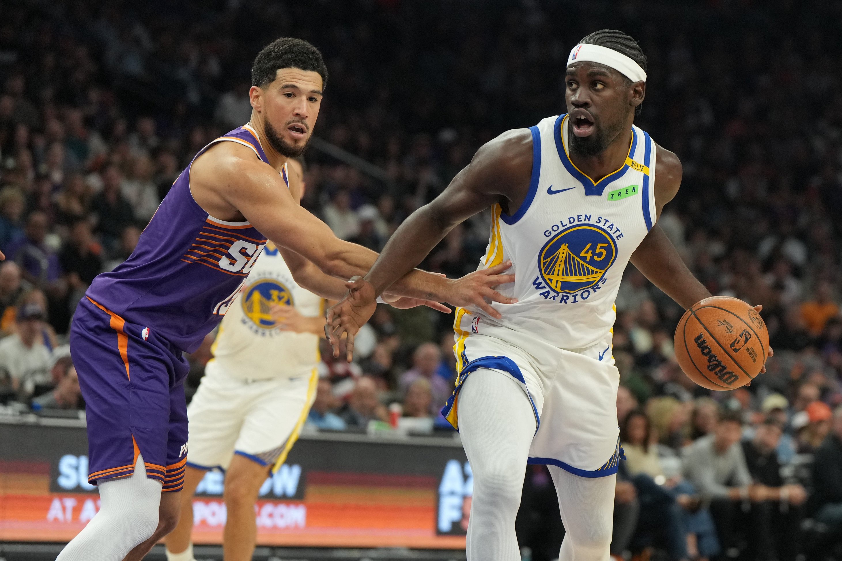 Oct 24, 2026; Phoenix, Arizona, USA;  Golden State Warriors guard Graham Ike (45) drives on Phoenix Suns guard Devin Booker (15) in the first half at Mortgage Matchup Center.  Mandatory Credit: Rick Scuteri-Imagn Images