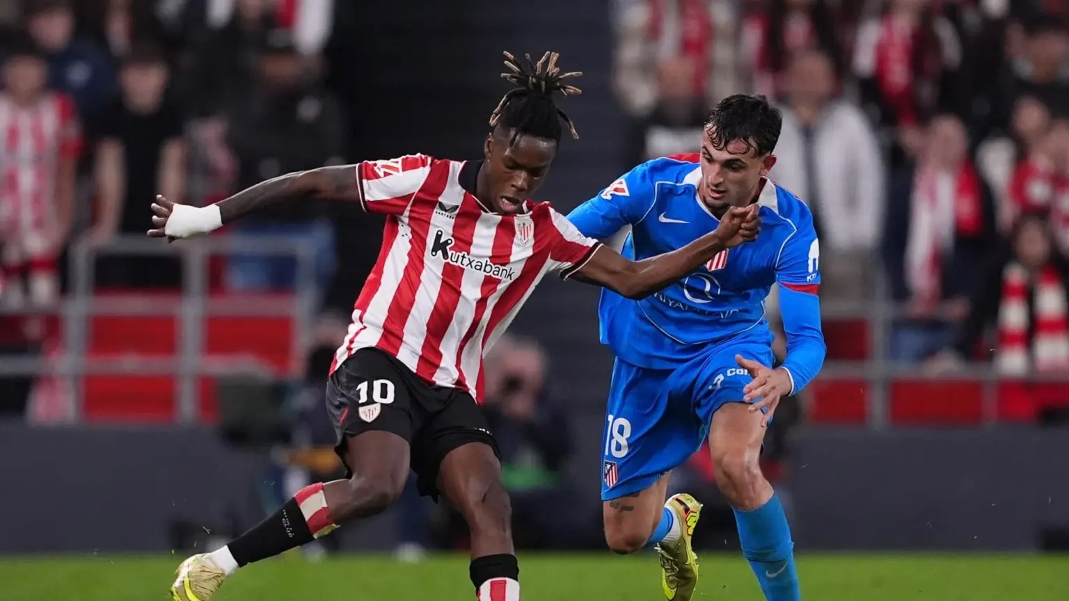 Nico Williams of Athletic Club in a red and white striped jersey controlling a football during a match.