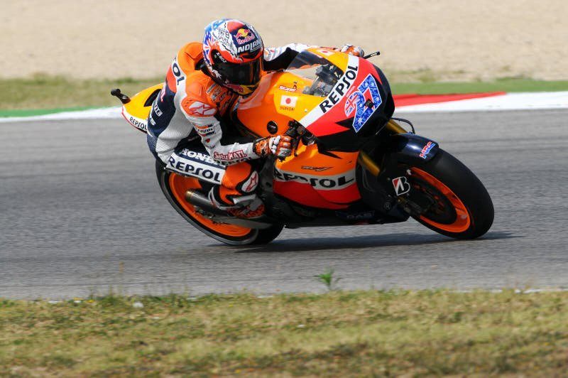 Rider in Repsol Honda leathers and helmet leaning into a corner on a Repsol Honda MotoGP bike on a racetrack