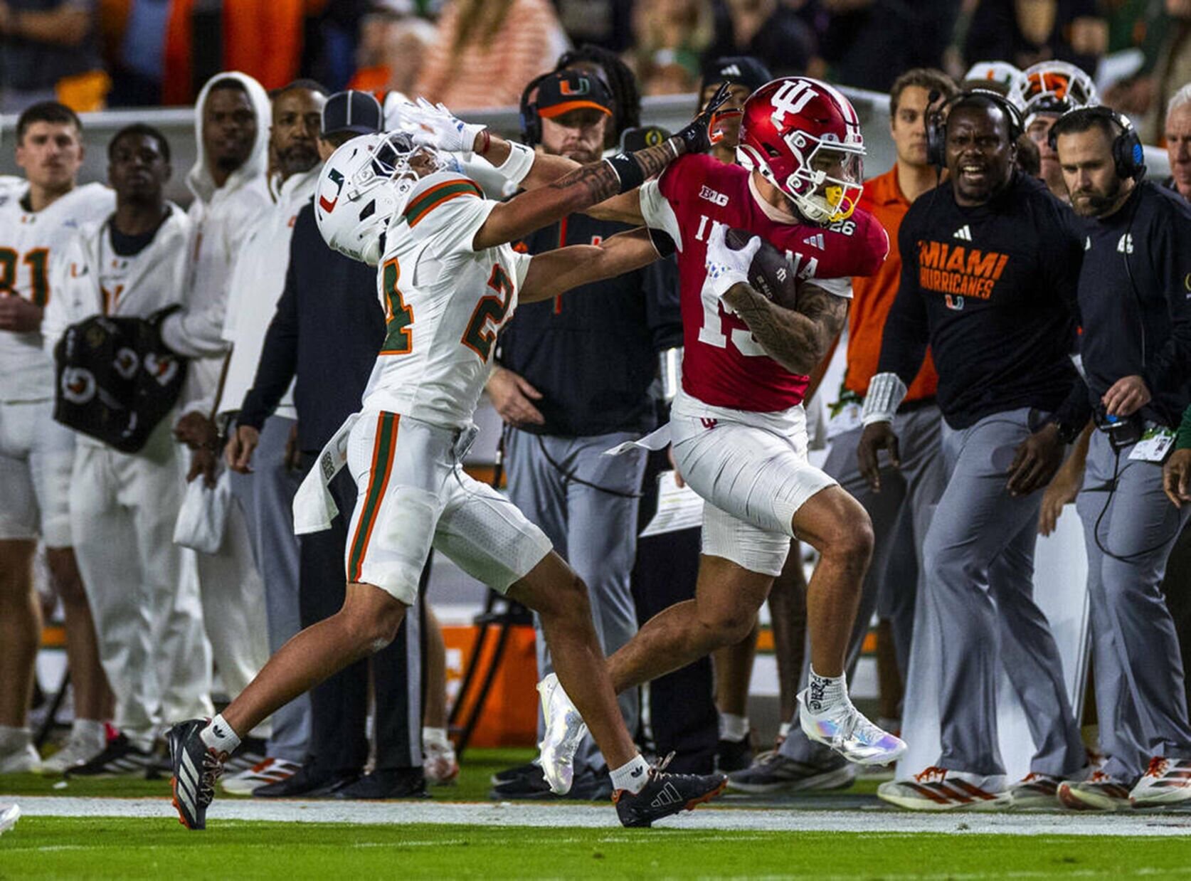 Indiana wide receiver Elijah Sarratt pushes away University of Miami defensive back Ethan O'Connor after a catch and run along the sidelines during the first half of the College Football Playoff national championship game at the Hard Rock Stadium on Mon...
