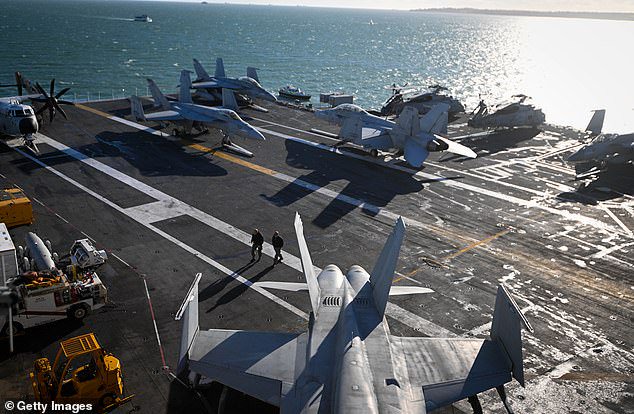 Navy personnel walk past F-18 jet fighters on the flight deck of USS Gerald R. Ford, on November 17, 2022 in Gosport, England. The US and UK have both exceeded their 2% GDP defence spending target