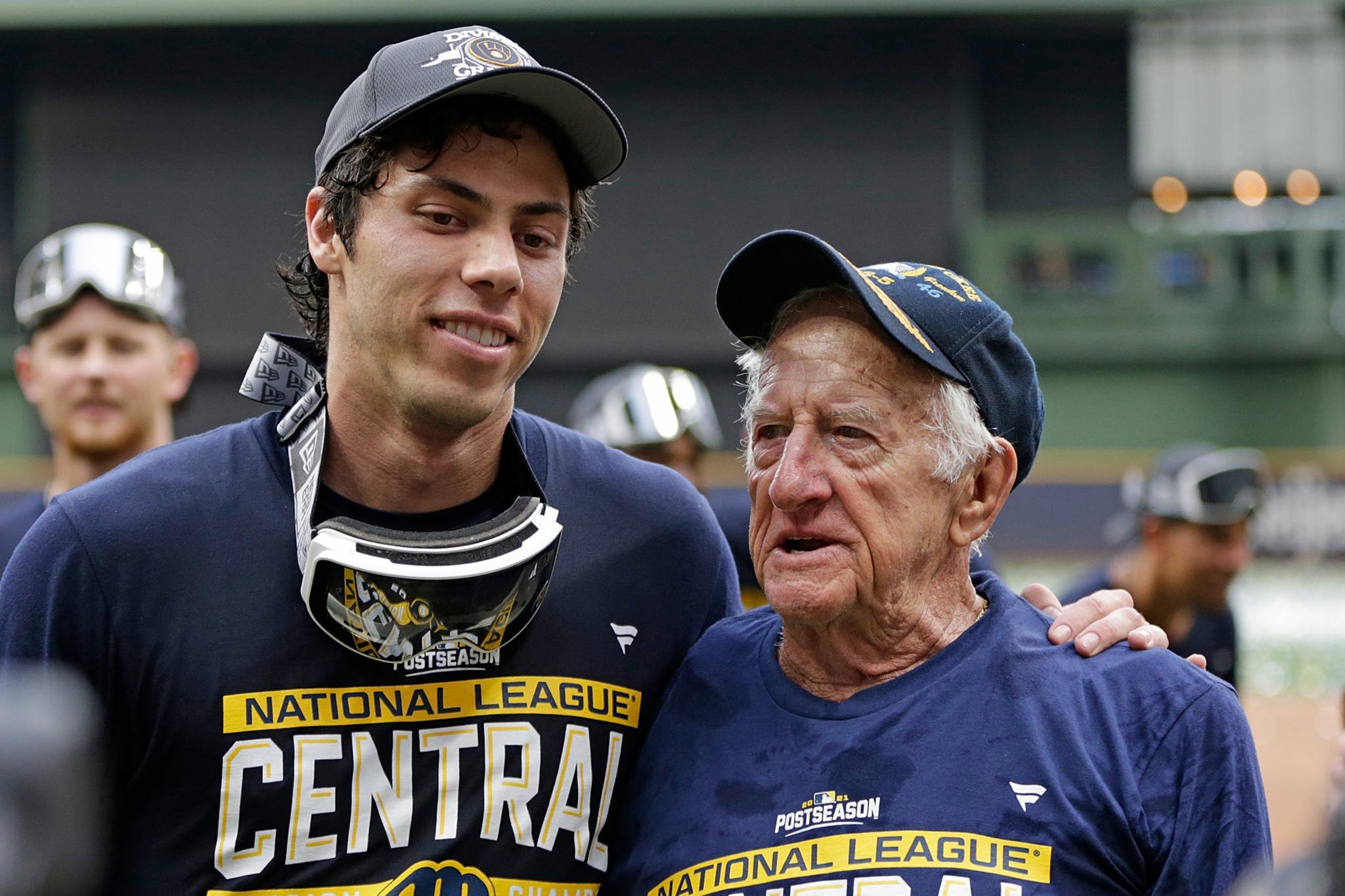 Christian Yelich and an older man wearing Milwaukee Brewers postseason shirts and hats.