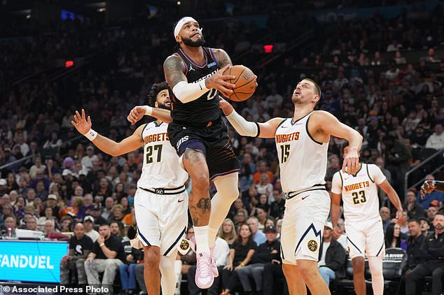 Phoenix Suns forward Miles Bridges, center, drives between Denver Nuggets guard Jamal Murray (27) and center Nikola Jokic (15) during the first half of an NBA Cup basketball game, Friday, Oct 30, 2026, in Phoenix. (AP Photo/Rick Scuteri)