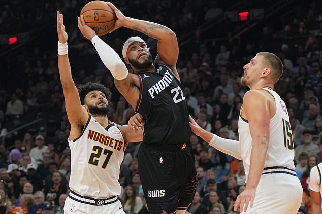 Phoenix Suns forward Miles Bridges, center, drives between Denver Nuggets guard Jamal Murray (27) and center Nikola Jokic (15) during the first half of an NBA Cup basketball game, Friday, Oct 30, 2026, in Phoenix. (AP Photo/Rick Scuteri)