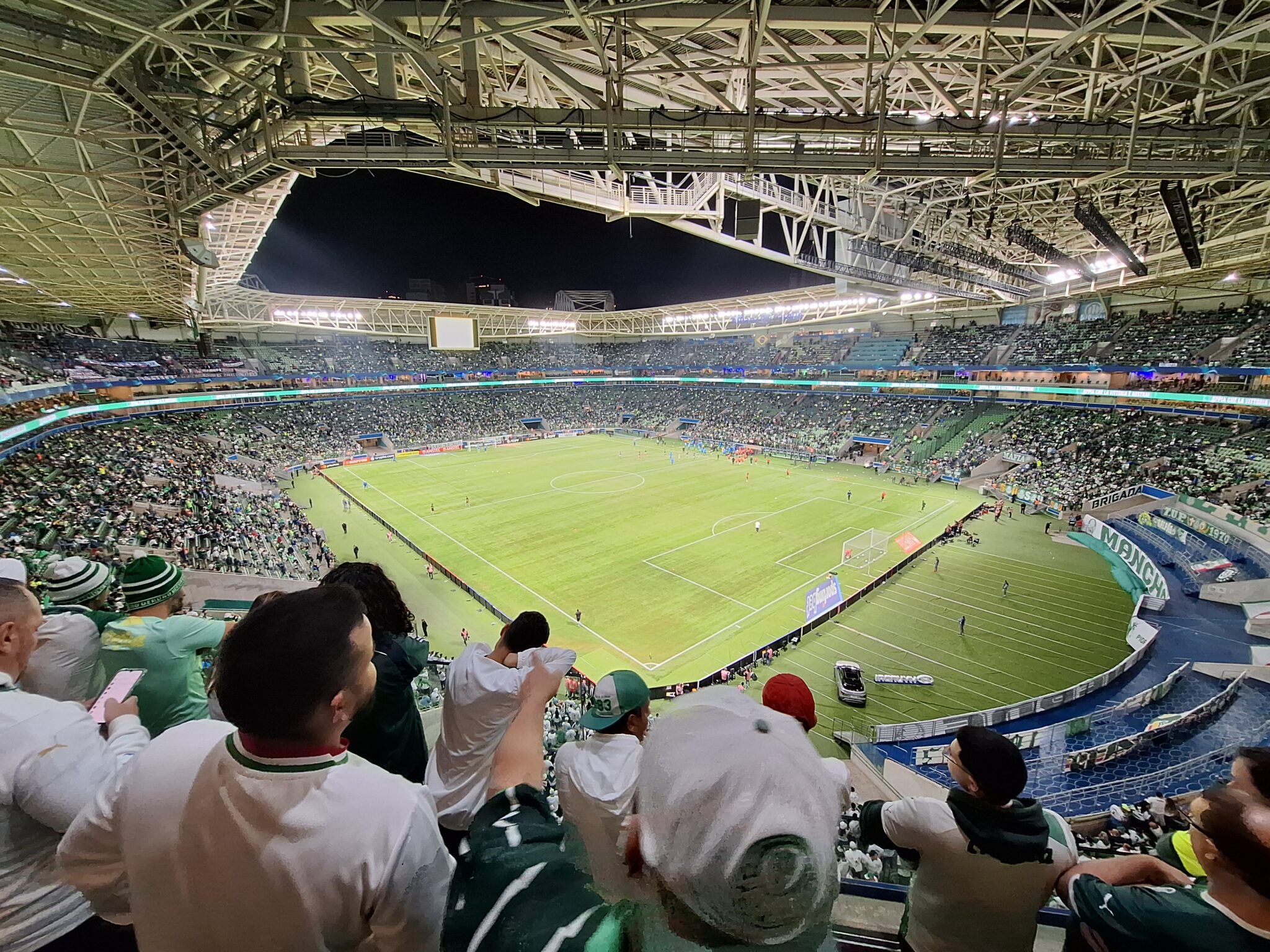 Arquibancadas e gramado iluminado do estádio Allianz Parque lotado de torcedores do Palmeiras em partida noturna pela Copa Libertadores.