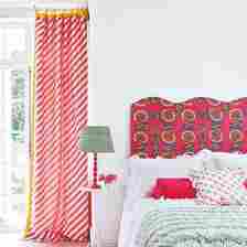 A bedroom with a patterned wavy headboard and striped curtains