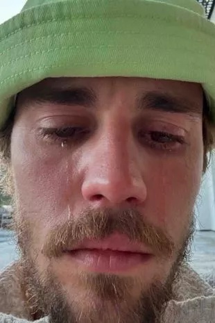 Justin Bieber cries while wearing a green bucket hat