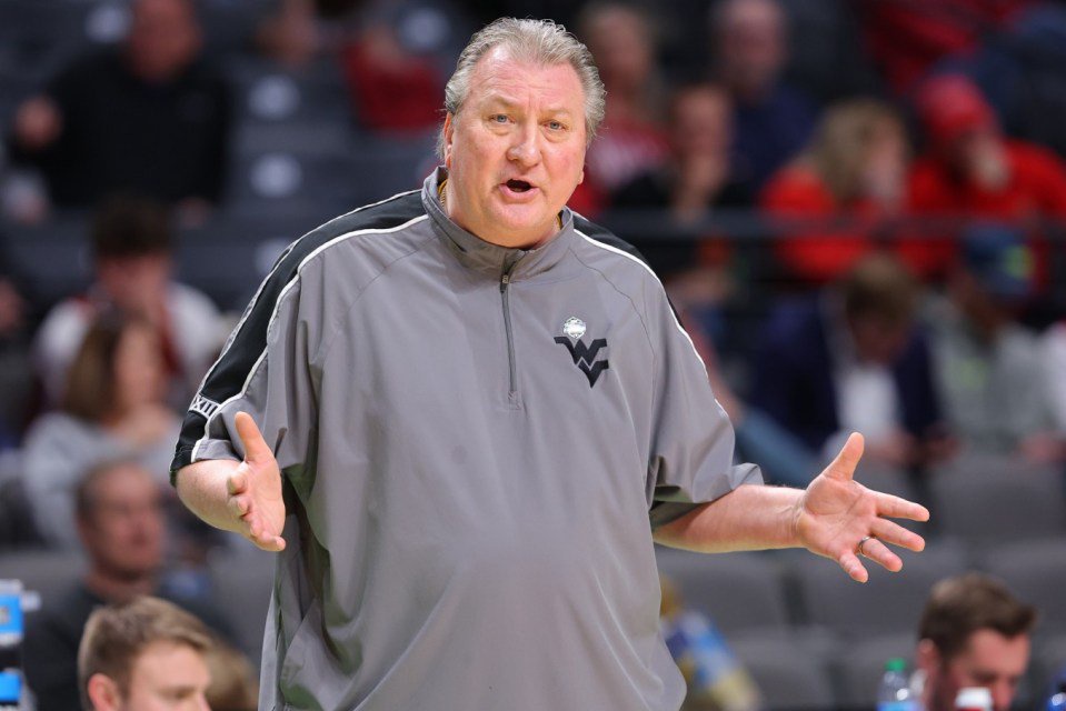 West Virginia basketball coach Bob Huggins gestures on the court.
