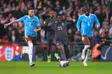 Kobbie Mainoo of England in action with Zeno Debast and Amadou Onana of Belgium  during the international friendly match between England and Belgiu...