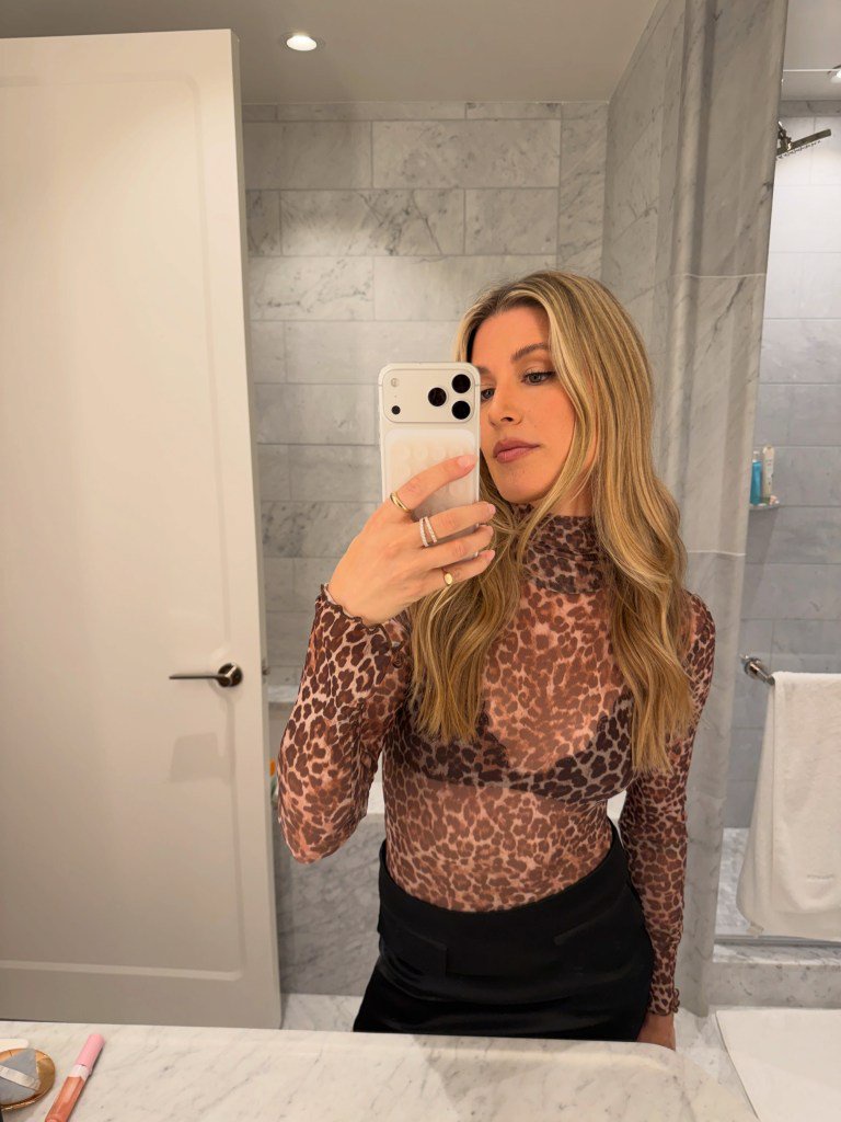 Eugenie Bouchard takes a mirror selfie in a bathroom, wearing a sheer leopard-print top.