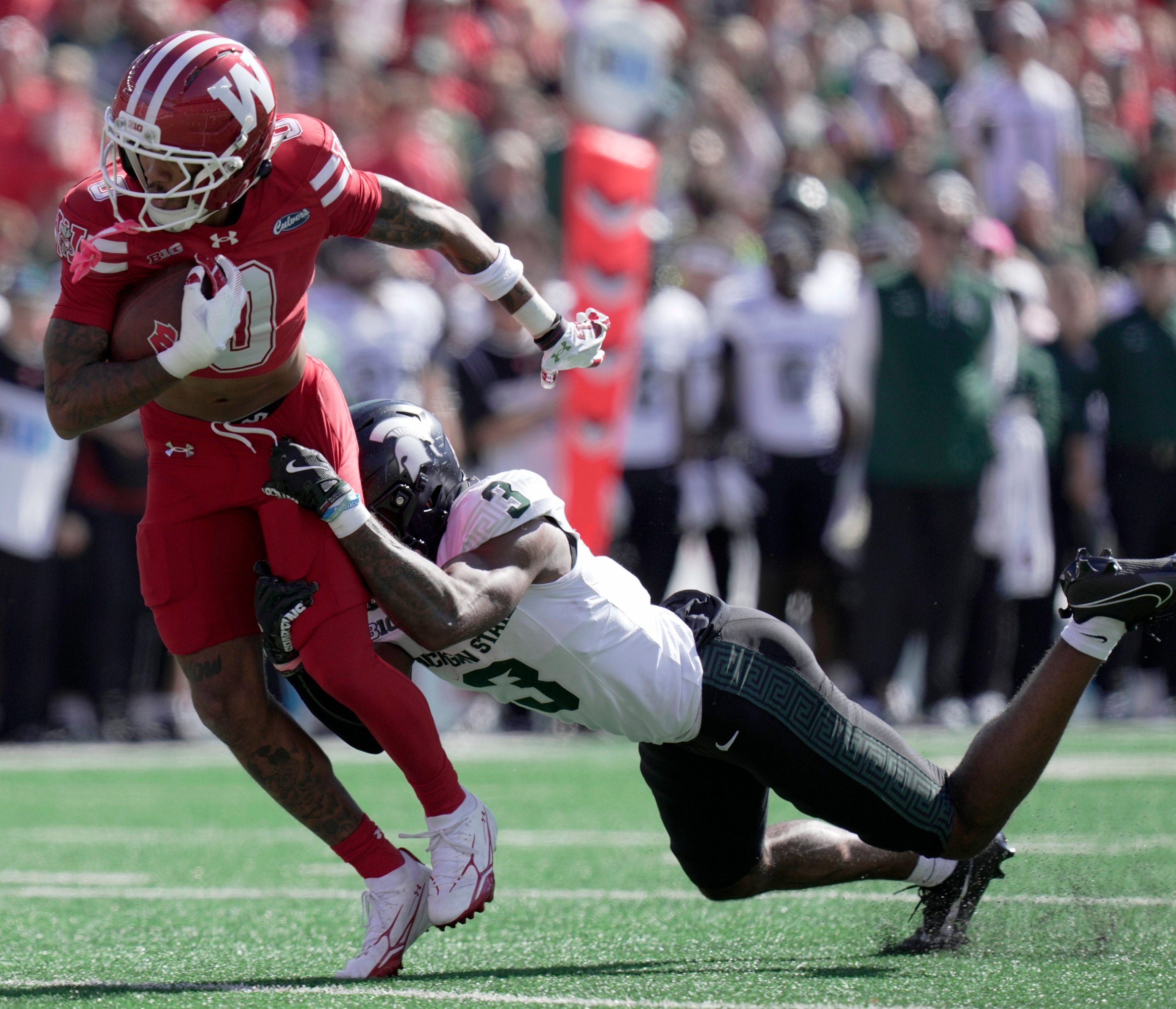 Wisconsin wide receiver Tyrell Henry (0) is tackled by Michigan State defensive back Tre Bell (3) after making a reception for a first down during the second quarter of their game Saturday, October 3, 2026 at Camp Randall Stadium in Madison, Wisconsin. 