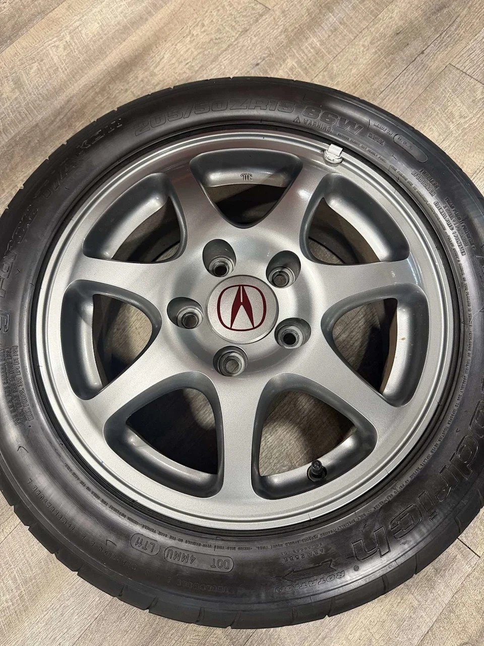 Seven-spoke 15-inch alloy wheel with five lug holes and Acura center cap from a 2000 Integra Type R